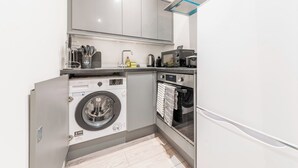 Una cucina compatta con lavatrice integrata, forno e microonde.