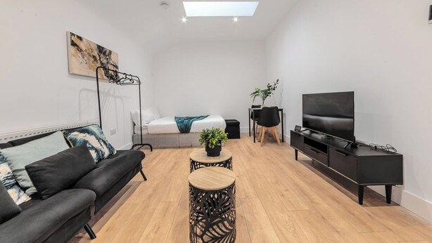 Una sala moderna con sofá, una mesa de centro, televisor y cama.