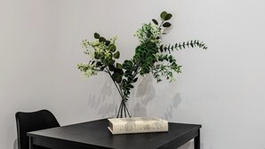 Una mesa negra con un libro titulado 'PALM SPRINGS' y un florero con follaje verde.