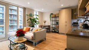 A modern apartment with a living room, dining area, and kitchen. - Modern Riverside Apartment | Balcony | Elizabeth Line (London)