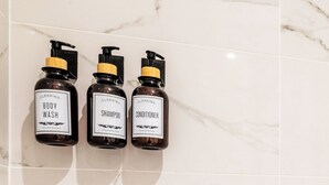 Drei Flaschen Badesseife, Shampoo und Spülung auf einer Marmorplatte.