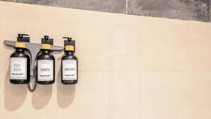 Three bottles of body wash, shampoo, and conditioner on a wall. - Cosy Serene Flat near the City Centre (Kent)