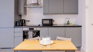 A compact kitchen with grey cabinets, a microwave, a kettle, and a small sink. - Cosy Serene Flat near the City Centre (Kent)