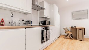 Una cocina moderna con armarios blancos, una campana extractora de acero inoxidable, un microondas y un horno.