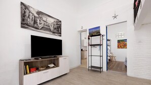 A modern living room with a flat-screen TV, a bookshelf, and a painting on the wall. - Holiday Home 'Ciccina' with Wi-Fi and Air Conditioning (Palermo)