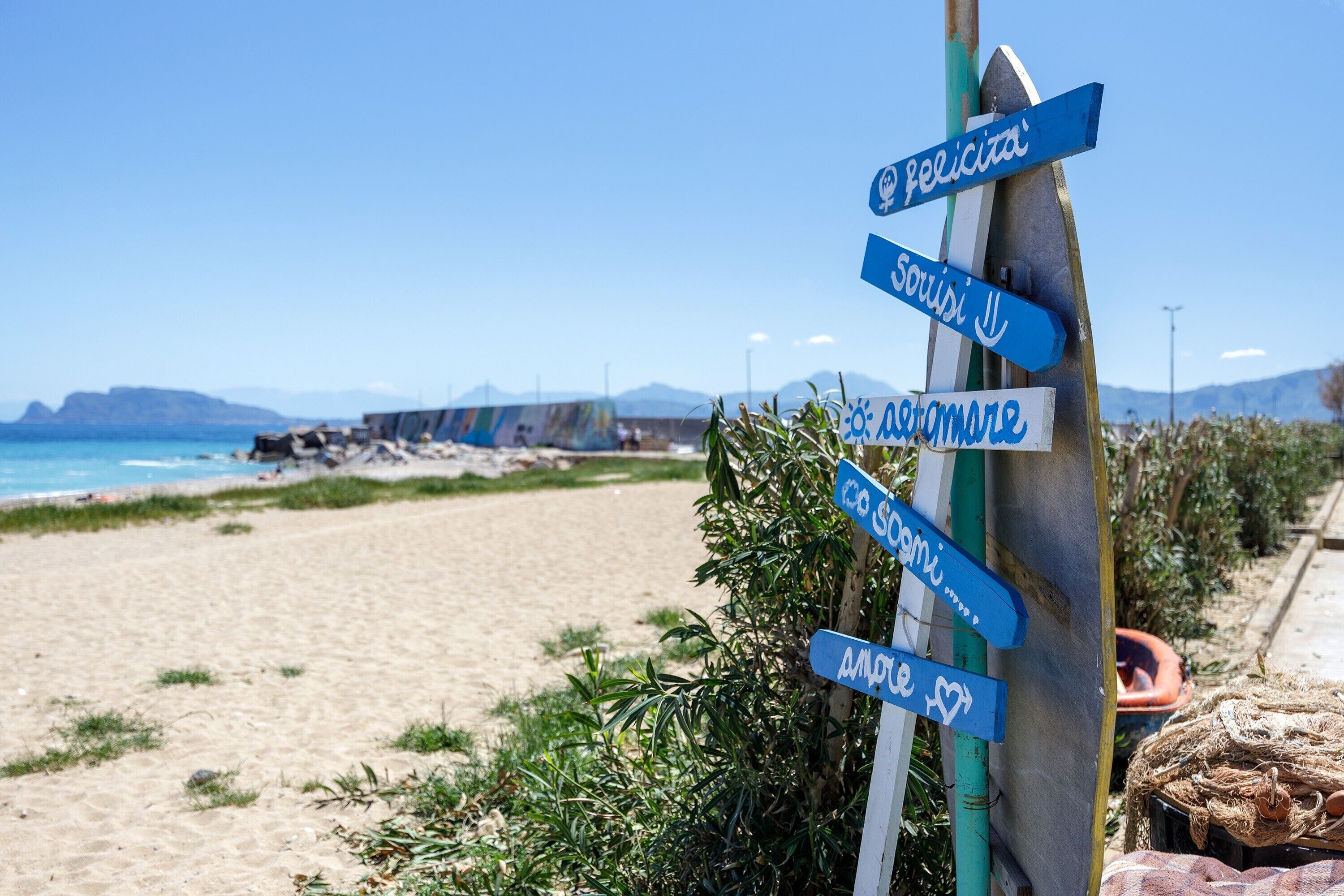 A beach with a signpost indicating directions to various locations.
