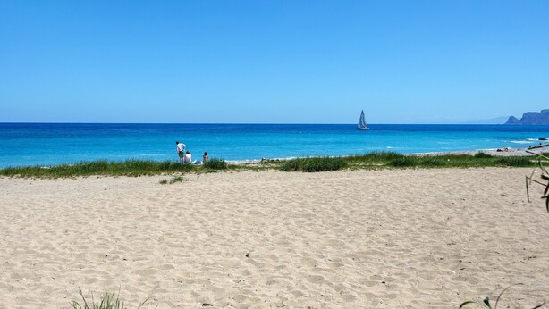 A beach with clear blue water, a sailboat in the distance, and a few people on the sand. - Holiday Home 'Ciccina' with Wi-Fi and Air Conditioning (Palermo)