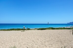 A beach with clear blue water, a sailboat in the distance, and a few people on the sand. - Holiday Home 'Ciccina' with Wi-Fi and Air Conditioning (Palermo)