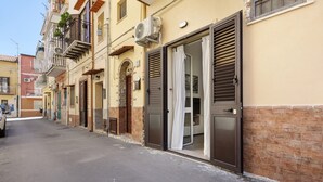 A row of buildings with closed shutters, a brick wall, and a parked car. - Holiday Home 'Ciccina' with Wi-Fi and Air Conditioning (Palermo)