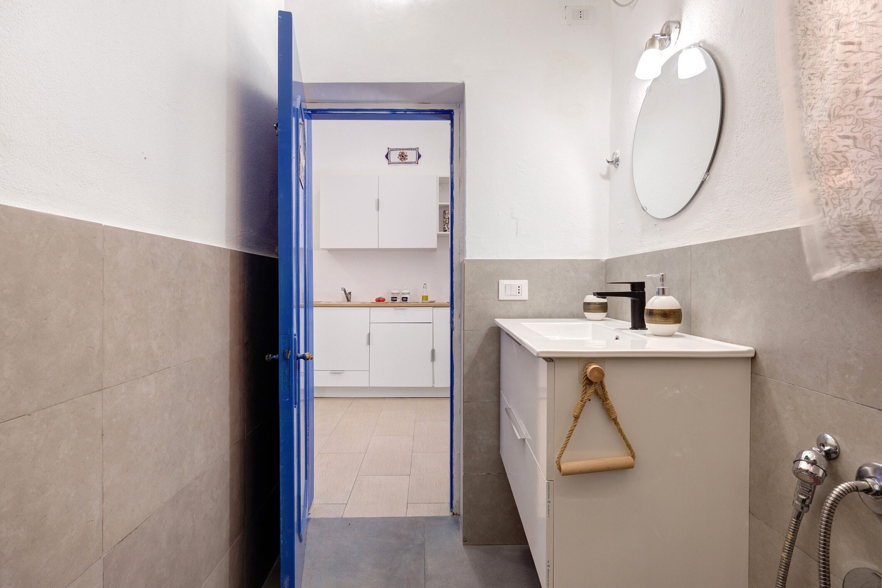 A bathroom with a white sink, a mirror, a towel rack, and a shower area.