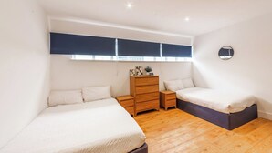 Un dormitorio con dos camas, un tocador, un espejo y una ventana con persianas.