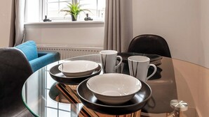 Una mesa de comedor con platos y tazas blanco y negro, una cubierta de vidrio y una silla.