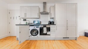 Una cocina funcional equipada con lavadora, horno, microondas y cafetera.