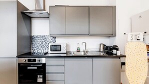 Een kleine keuken met een magnetron, oven en spoelbak.