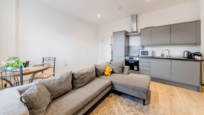Een moderne woonkamer met een bank, een eettafel en een keukenhoek.