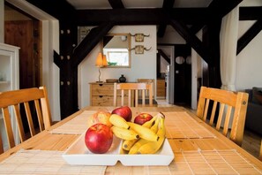 Ein Holztisch mit Obstschale, Holzstühle, ein Holzschrank und ein Spiegel an der Wand.