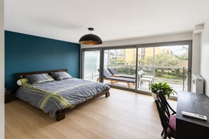 Et soveværelse med seng, skrivebord, stol og en balkon med udsigt.
