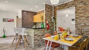 A modern kitchen with a stone backsplash, a dining area with a table set for two, and a bar area. - Villa 'Casa Do Sol' in Tavira (Luz)