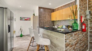 A modern kitchen with a central island, wooden cabinets, and a fire extinguisher. - Villa 'Casa Do Sol' in Tavira (Luz)