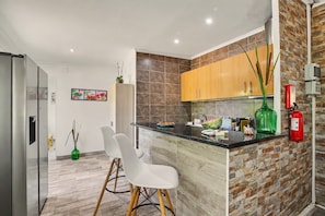 A modern kitchen with a central island, wooden cabinets, and a fire extinguisher. - Villa 'Casa Do Sol' in Tavira (Luz)