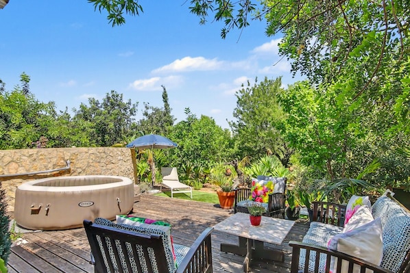 An outdoor patio with a hot tub, seating area, and potted plants.