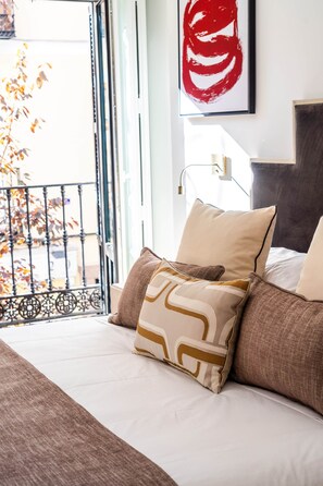 A hotel room with a bed, pillows, a large window, and a red abstract painting on the wall. - Príncipe Executive Residence (Madrid)
