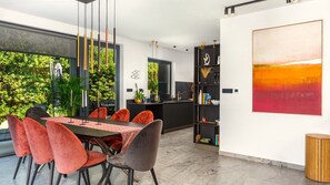 Un espace repas moderne, avec une table, des chaises et une vue sur la verdure environnante.