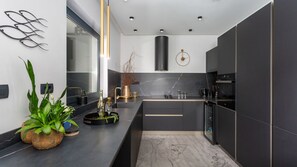 Une cuisine moderne avec des meubles de couleur sombre, un plan de travail en marbre et un design minimaliste.