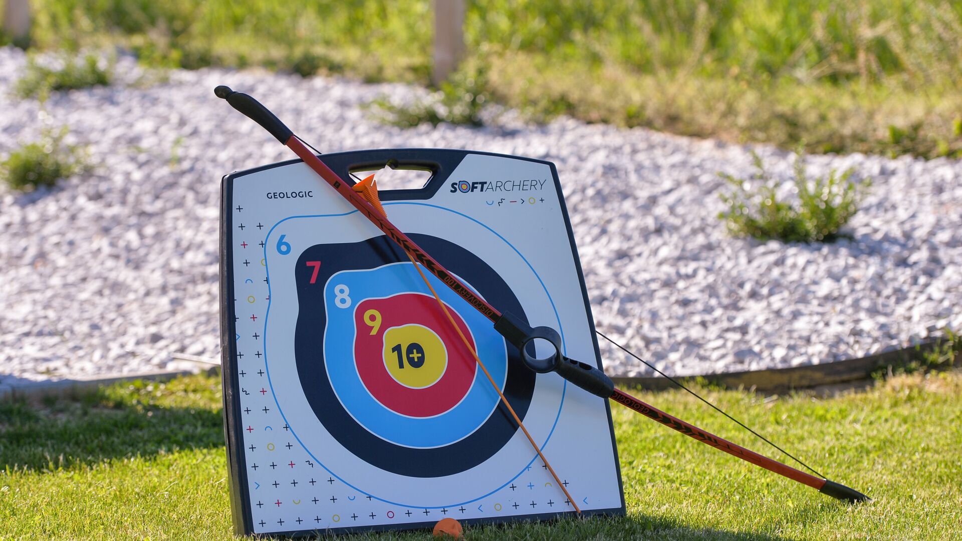 A target board with numbered scoring zones, a bow, and a quiver.