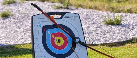 A target board with numbered scoring zones, a bow, and a quiver.