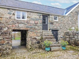 A stone building with a traditional design, featuring a large doorway, a small window, and a door.