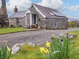 A stone house with a sloped roof, a small porch, and a solar panel.