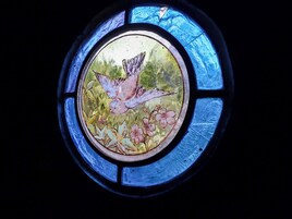 Una ventana de vitral con diseño de aves y flores.