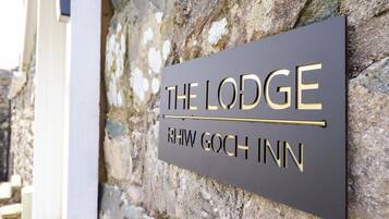 Een bord met 'The Lodge', daaronder staat 'RHWW GOCH INN'.