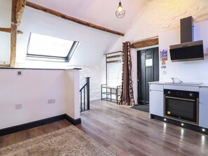 A kitchen with a built-in oven, a microwave, and a television above it. There is a window and a door leading to another room. - The Lodge House at Rhiw Goch Inn (Blaenau Ffestiniog)
