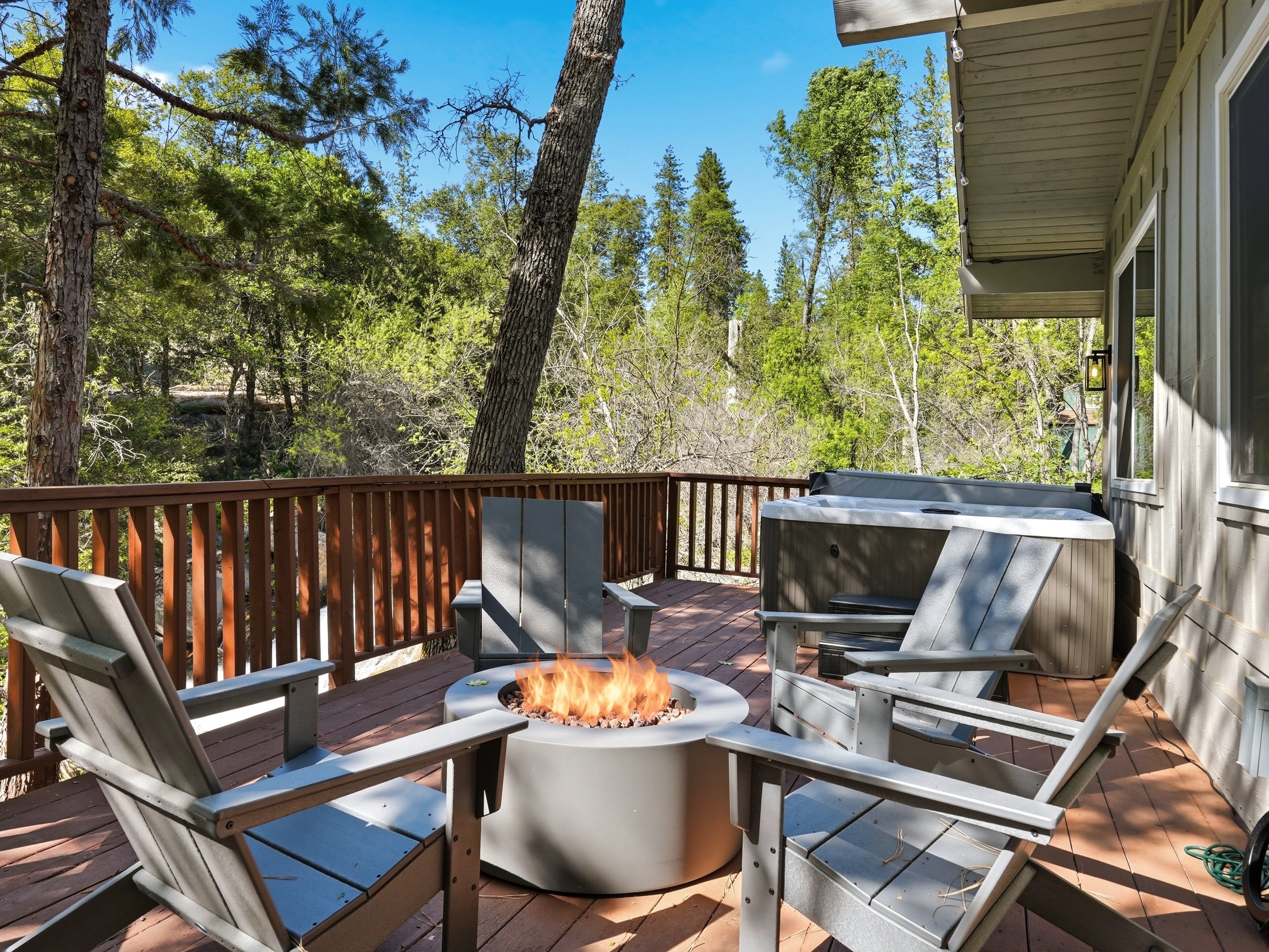 A deck with outdoor furniture, a fire pit, and a view of a forest.