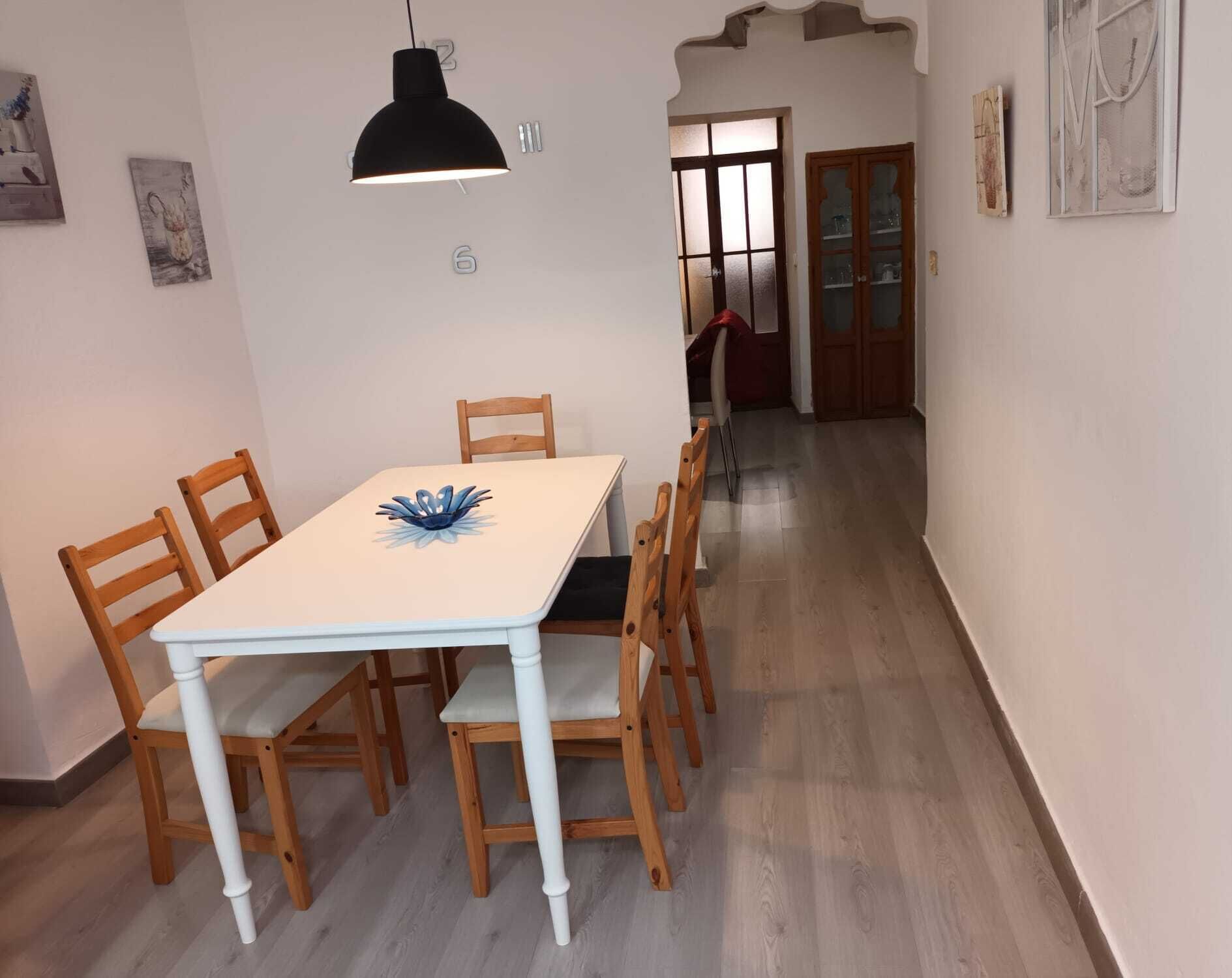 A dining area with a table, chairs, and a pendant light.