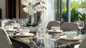 A dining table set with white bowls, wine glasses, and a vase of white flowers. - Ozone Sanctuary 3BR Private Pool Villa (Choeng Thale)