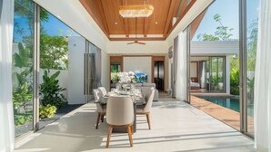 A modern dining area with a glass wall, a wooden ceiling, and a pool visible through the glass. - Ozone Sanctuary 3BR Private Pool Villa (Choeng Thale)