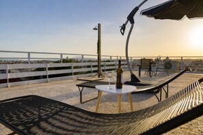 A rooftop terrace with a table, chairs, a bottle of wine, and a view of the cityscape. - Bay View - Bright Modern Penthouse in Center (Kalamata)