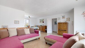Ein Wohnzimmer mit Sofa, Essbereich und Küche.