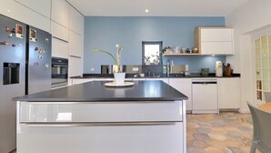 Cozinha moderna com ilha central, armários brancos e uma parede de destaque azul.