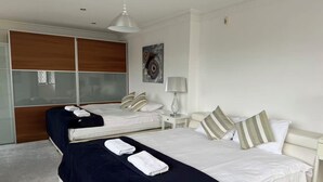 Ein Hotelzimmer mit zwei Betten, einem großen Spiegel, einem Gemälde, einer Lampe und einem Deckenventilator.
