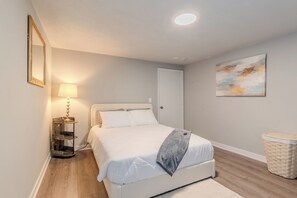 Une chambre à coucher avec un lit, une lampe, un tableau et un panier en osier.