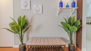 Ein Zimmer mit einer Bank, zwei Blumentöpfen und zwei Kunstwerken an der Wand.