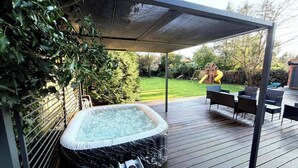 A hot tub under a covered patio with a view of a backyard. - 2 Bed - Sleeps 5 - Garden - Hot-tub (London)