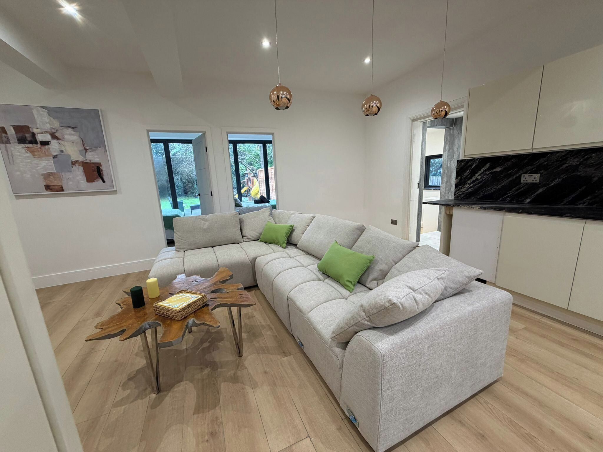 A modern living room with a sectional sofa, a wooden coffee table, and pendant lighting.