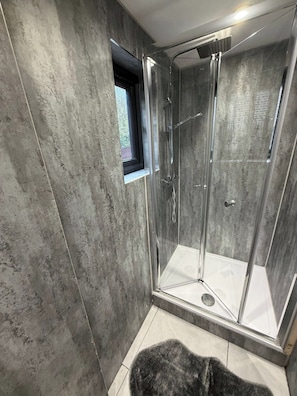 A glass-enclosed shower with a window, tiled floor, and a small rug. - 2 Bed - Sleeps 5 - Garden - Hot-tub (London)