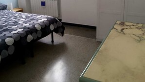Un dormitorio con una cama, un radiador, una ventana y una mesa verde.