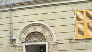 Un edificio con una amplia entrada en arco, una puerta visible y el número 21 en la pared.